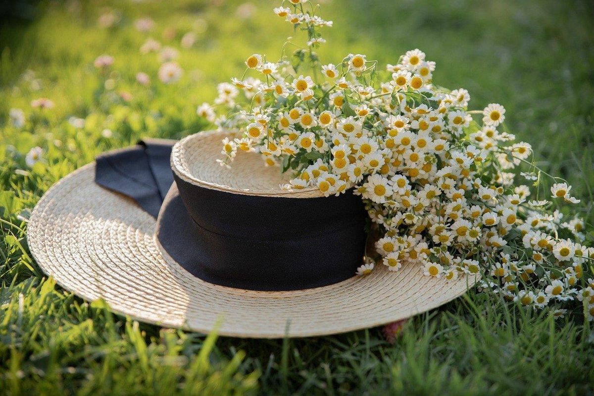 Élégance champêtre : chapeau de paille et fleurs pour un style tête haute.