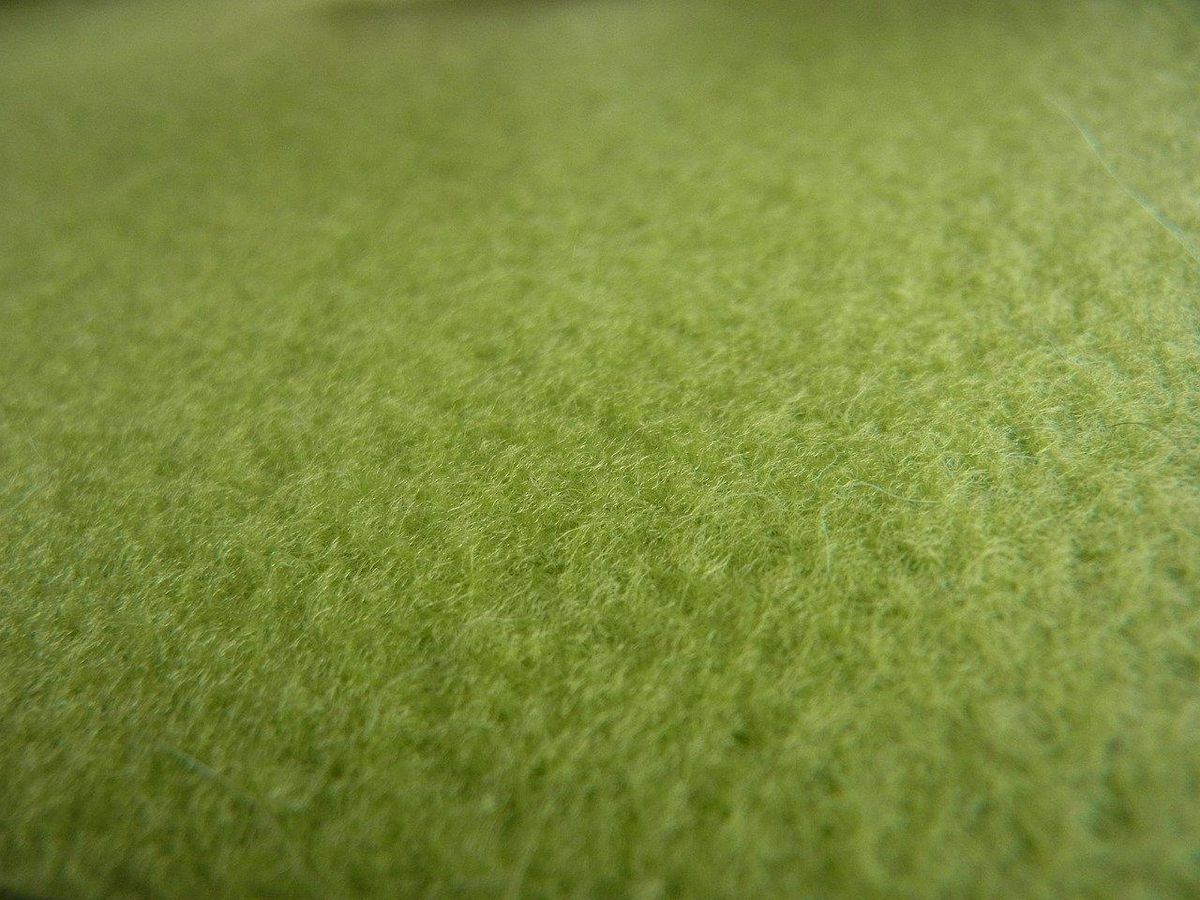 La texture du feutre vert: la laine, une fibre naturelle prisée dans la mode écoresponsable.