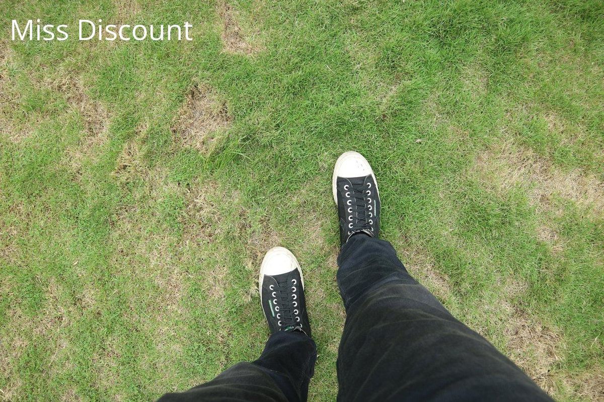 Sneakers noires sur herbe : le style casual à vos pieds.